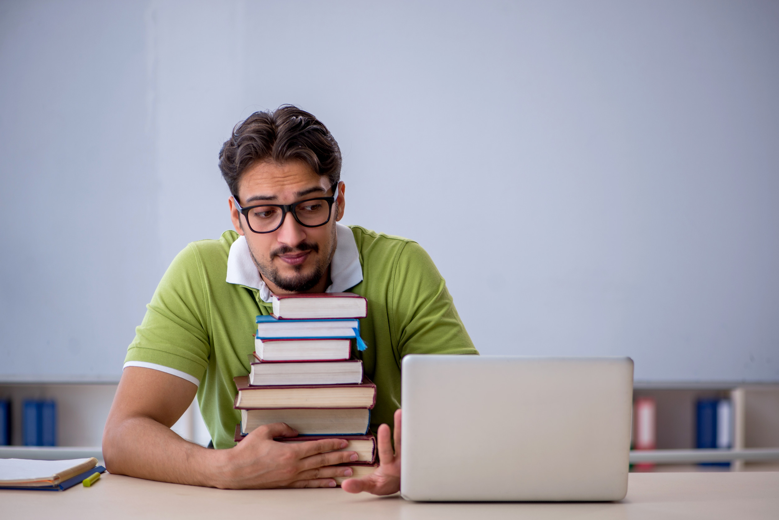 Ragazzo con pila di manuali affronta lo studio di un concorso pubblico
